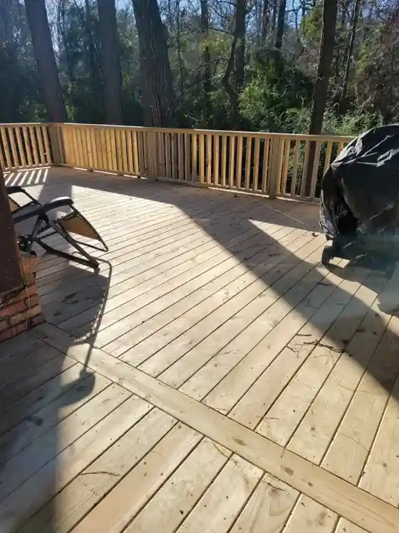Pine deck laid with diagonal boards and a matching rail beside a pine tree