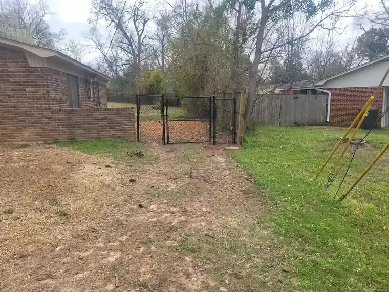 Black chain link run with a walk gate along a brick house yard